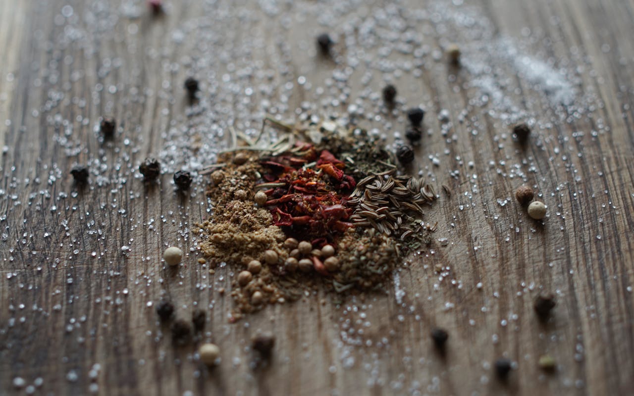 About A selection of mixed spices and salt on a rustic wooden background.