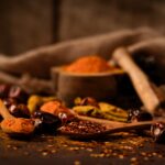 A close-up of rustic spices such as chilies and turmeric on wooden spoons, highlighting food textures.